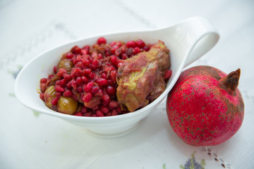 The Living Pomegranate is on a white tablecloth . Roasted pomegranet seeds . Baked pomegranate seeds and chicken .