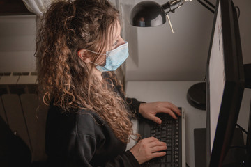 Fototapeta na wymiar young woman wearing a surgical mask working on computer