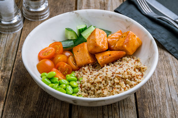 Poke with salmon and quinoa on wooden table