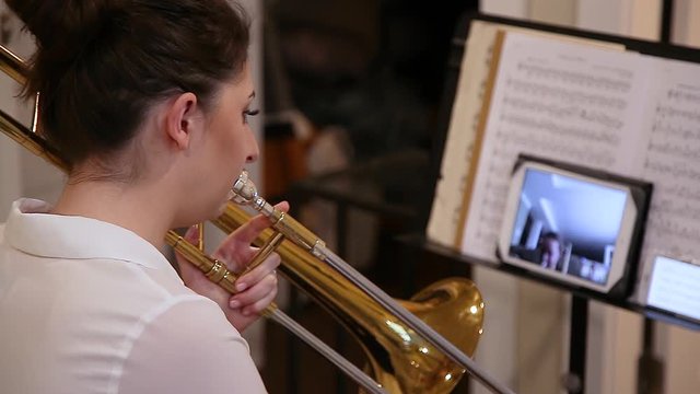 An attractive young brunette caucasian woman working from home by teaching music via video call during the Covid 19 crisis. 24FPS HD.