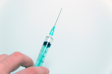 Medical syringe in hand on a blue background
