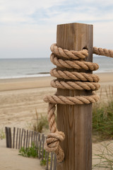 Rope Wrapped Around a Post in Front of Wild Grass and Short Barrier Fence with Crashing Waves on a Beach at Corolla, North Carolina