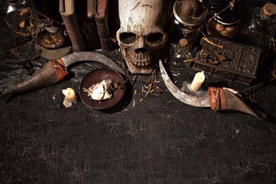 High Angle View Of A Skull With Lit Candles And Books On A Black Table - Cool For Backgrounds