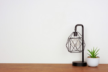 Home decor on a shelf. Industrial style lamp and succulent plant. Wooden shelf against a white wall...