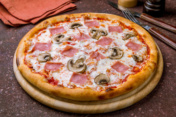 Pizza with ham and mushrooms on concrete table