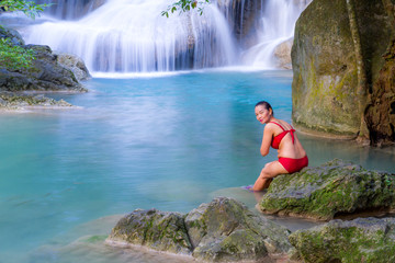 Woman with red bikini enjoy water at Erawan Waterfall and natural