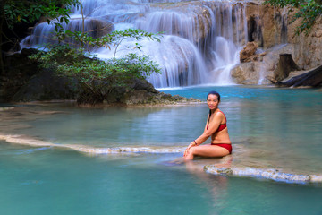 Woman in red bikini beautiful at Erawan Waterfall and natural