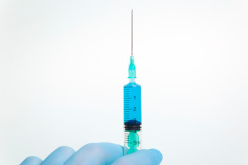 Medical syringe in hand on a blue background
