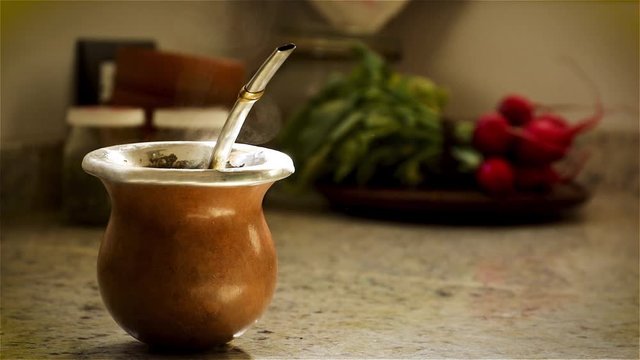 Close up serving the traditional argentinian drink "mate" in a hollow pumpkin bowl with a beautiful alpaca bulb.