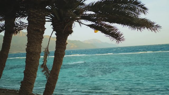 Kite surfing in beautiful clear water in Dahab Egypt. Exploring the blue water with mountains in the background and people windsurfing and kite surfing, slow motion, full hd