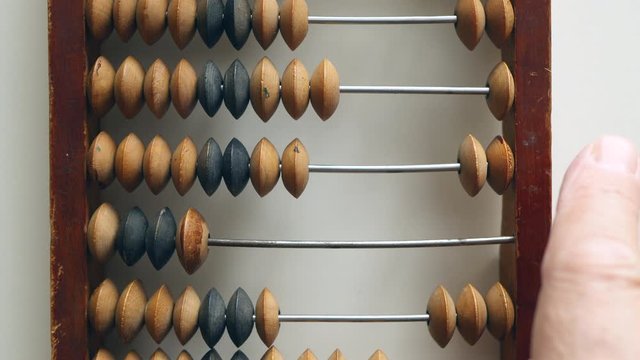 A Elderly Man Moves Wooden Knuckles On A Outdated Vintage Wooden Abacus On A White Desk Close-up. Natural Daylight