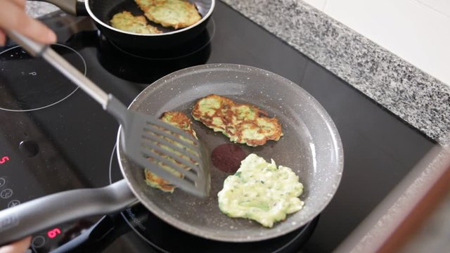 Image of process frying zucchini pancakes in frying pan in kitchen