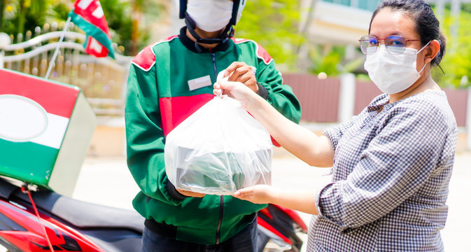 Motorbike delivery man send pizza to asian pregnant woman.Delivering Food In City.Delivery man of takeaway with isothermal food case box driving find home.Express food delivery service.Stay at home. - Powered by Adobe