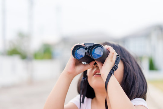 Smart asian kid girl looking up to sky and the moon playing outdoor astronomy concept with binoculars.child girl with spyglass.Travel adventure, Explore world,Imagination dream education concept.