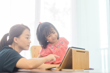 Covid-19 Coronavirus and Online learning from home, Home school kid.Little asian girl study with online learning class with mother work from home with tablet.Self isolation, Social distancing concept.