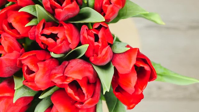 Top View Rotating Of Beautiful Bouquet Red Tulips In Vase Standing On A Gray Wooden Background On The Left Side  Close-up.