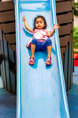 Pretty asian little girls while sliding in a playground