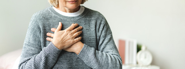 Senior adult elderly women sit on bed with chest pain suffering from heart attack in the...