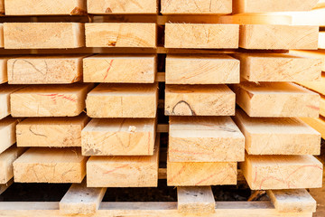 Stack of new wooden studs at the lumber yard. Timber on the construction site to dry. Background of sawed and processed wood of coniferous breeds.