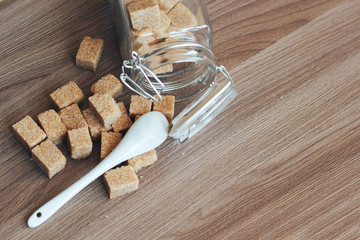 Brown cane refined sugar in a jar on a wooden background.