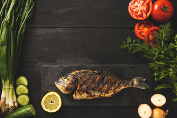 Cooked dorado fish on a black stone