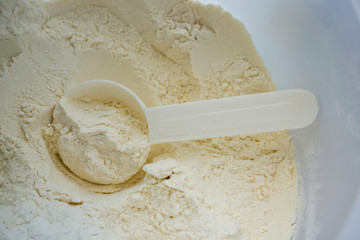 measuring spoon for protein, flour, white yellowish friable material ingredient on a light...