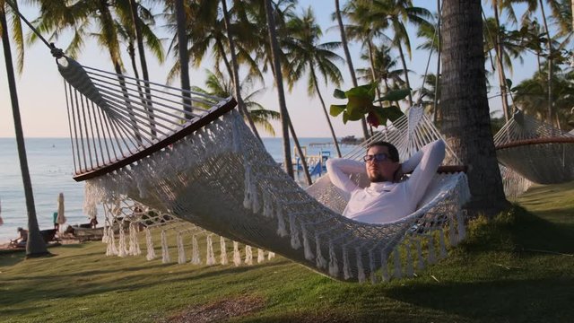 Nothing is bothering him now. Relaxing in swinging hammock on the beach