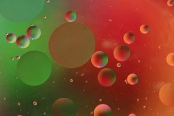 macro of oil mixed with water on colorful red, pink, green and orange background, colourful circles, copy space, vertical