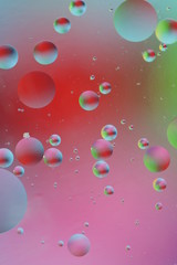 macro of oil mixed with water on colorful red, pink, green, blue background, colourful circles, copy space, vertical