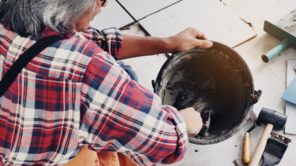 Construction workers or technicians is mixing the cement in the bucket using a trowel to sit on the...