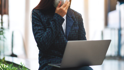 Closeup image of a sick woman wearing protective face mask, using laptop computer for Healthcare and Covid-19 concept