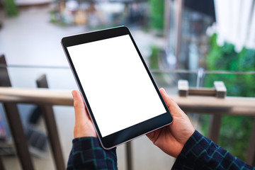 Mockup image of a woman holding black tablet pc with blank white desktop screen indoors