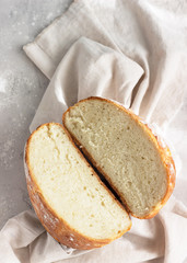 Round loaf of freshly backed artisan sourdough bread. No knead bread. Top view. Light grey concrete background.
