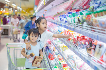 Asian children girl  on the cart shopping choose to see fresh food in department store.