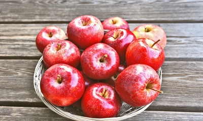 A lot of fresh Royal Red Gala apples in basket on wooden background.