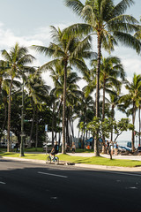 Fototapeta na wymiar Waikiki, Honolulu - August 27th 2019: The view from Kalakaua Ave of people enjoying the beautiful sunny Waikiki Beach in the morning.