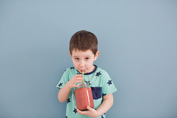 Cute toddler boy drink healthy smoothie from glass mason jar