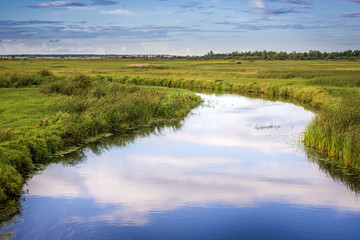 Clouds reflecting in the Biebrza River, view from a bridge in Dolistowo village, Poland