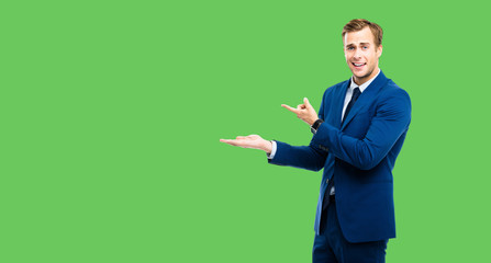 Businessman showing something, isolated against green color background. Copy space for some slogan...
