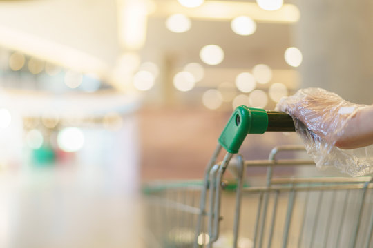 Blurred of supermarket with hand hold empty shopping cart.