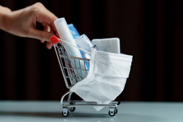 Hands pushing shopping cart and sanitizer products with protective face mask corona virus or...