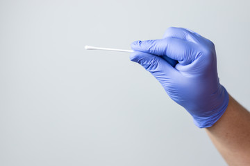 blue gloved hand holding coronavirus nasal test stick, or covid-19. Coronavirus test concept.
