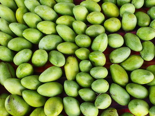 Raw mangoes collected from the garden are arranged in a community store to sell to customers. Raw mangoes have a green color, have a sour taste - ripe mangoes have a yellow, sweet taste.
