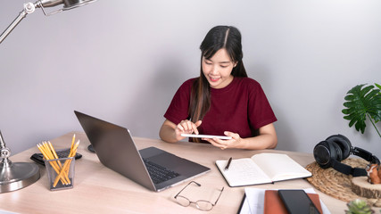 A young, beautiful relaxing business asian girl use a laptop working remotely from home on desk as a freelancer, quarantine for Coronavirus and smart working concept.