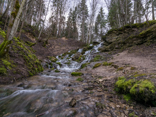 Obraz premium A stream of water flowing over rocks and creating a waterfall effect.