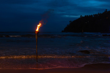 Burning torch on the sandy beach of the ocean