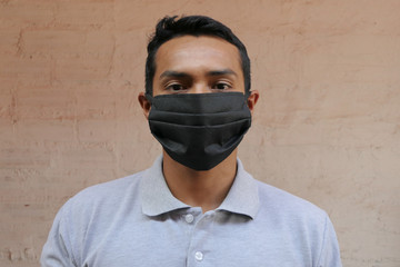 Young Latino man in a medical mask. Close-up of a man wearing a mask to protect himself against infection with the influenza virus or coronavirus.
