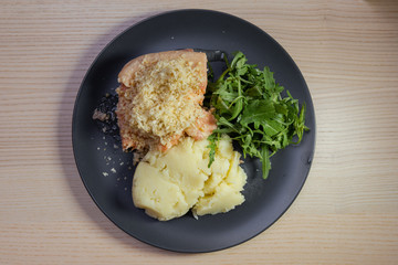 A plate of salmon, rocket salad, and mashed potato.