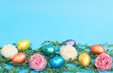 Fototapeta na wymiar Decorated Easter eggs lie on green leaves with pink and white flowers on the blue background. Happy Easter holiday concept. Greeting, invitation card. Flat lay style with copy space.