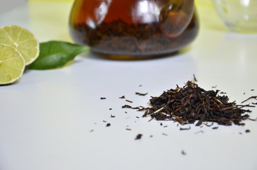 Transparent teapot with black tea, dry tea brewing on the table, bergamot slices, or lemon or lime on a white background